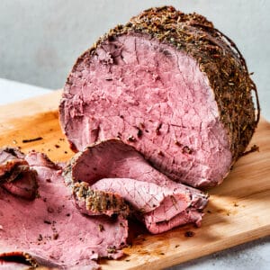 roast beef on a wood cutting boards, with some of it sliced
