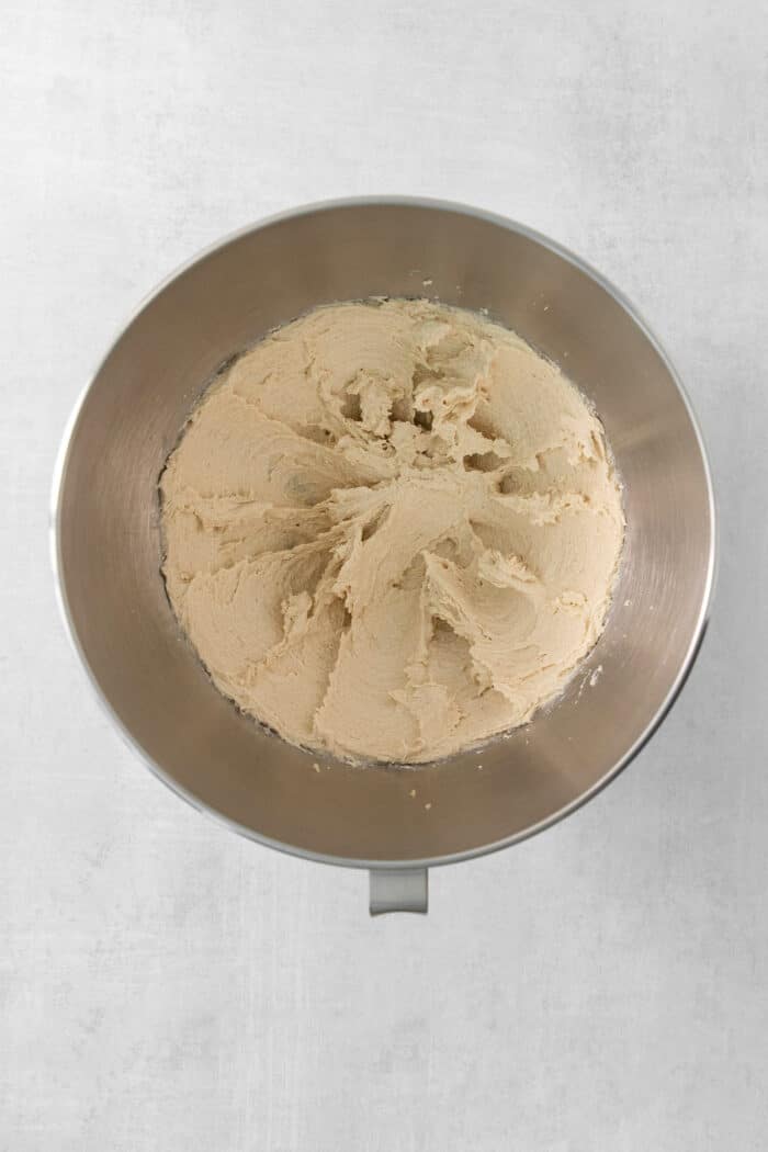 This Banana Coffee Cake features a tender banana bread cake layered with an oat streusel and topped with an optional vanilla bean glaze. A metal bowl of blended butter and sugar.