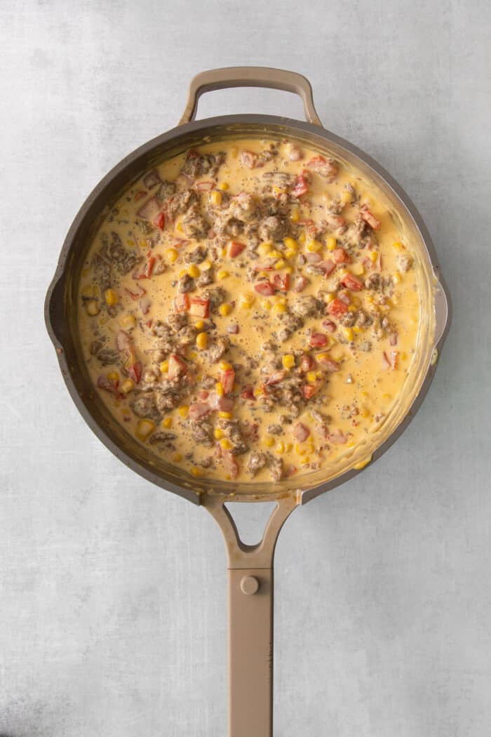 This gorgeously cheesy Sausage Dip takes a creamy base of Velveeta and sour cream and swirls it with spicy sausage and juicy corn kernels. Corn and Rotel tomatoes are added to a skillet full of cooked sausage and melted cheese.