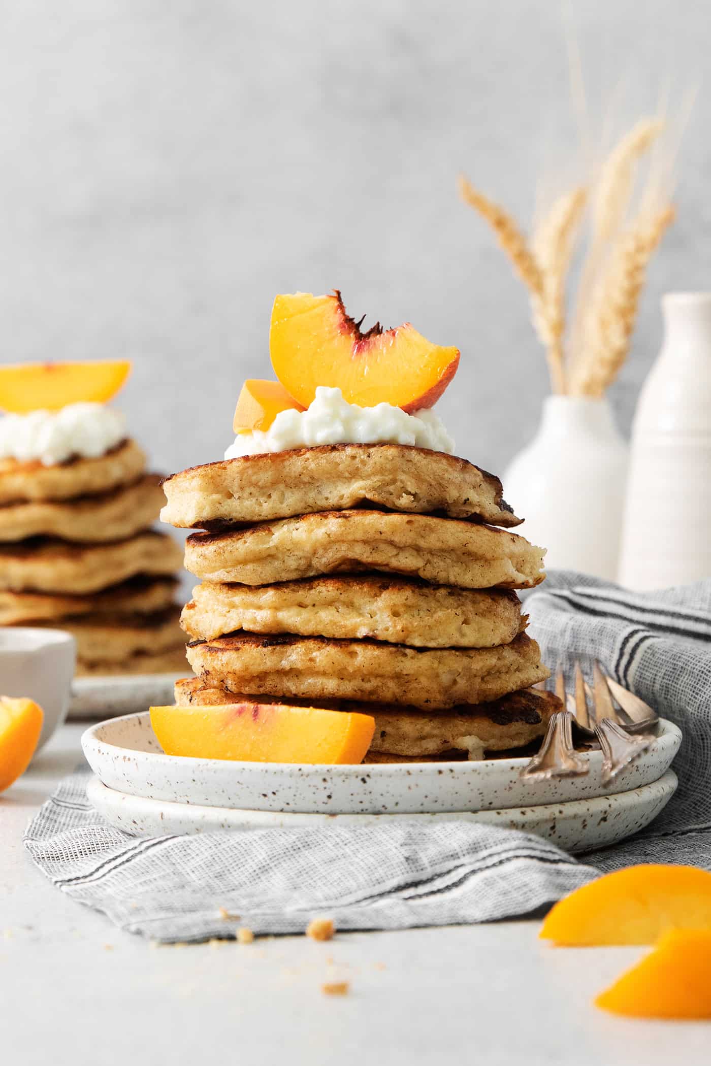 rotein-packed Cottage Cheese Pancakes are light and fluffy, flavored with cinnamon and vanilla, and rich and creamy from cottage cheese. Peach slices and whipped cream top cottage cheese pancakes with more seen in the background.