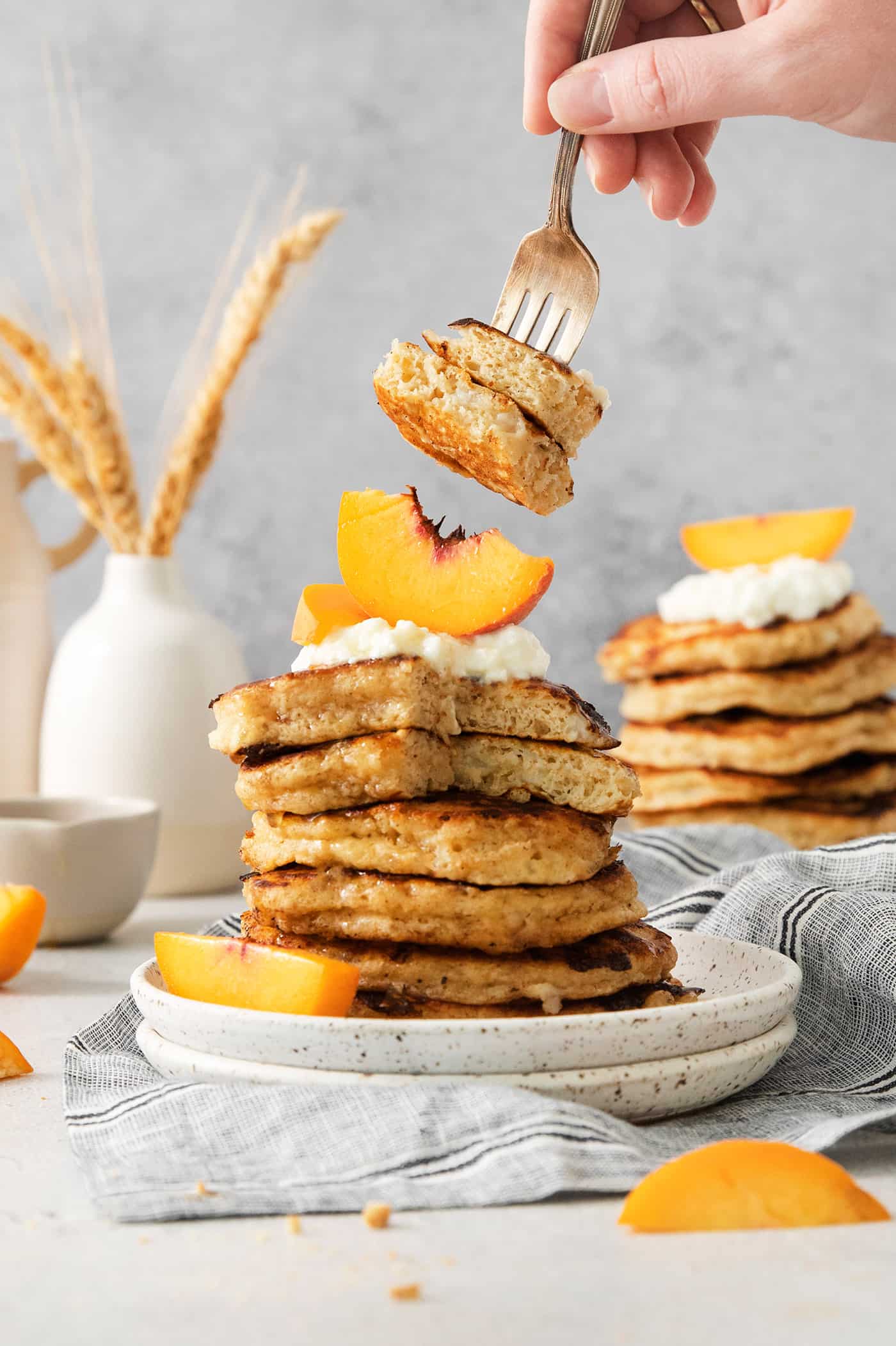 rotein-packed Cottage Cheese Pancakes are light and fluffy, flavored with cinnamon and vanilla, and rich and creamy from cottage cheese. Two bites of cottage cheese pancake are picked up with a fork, with the stack topped with whipped cream and peaches below.