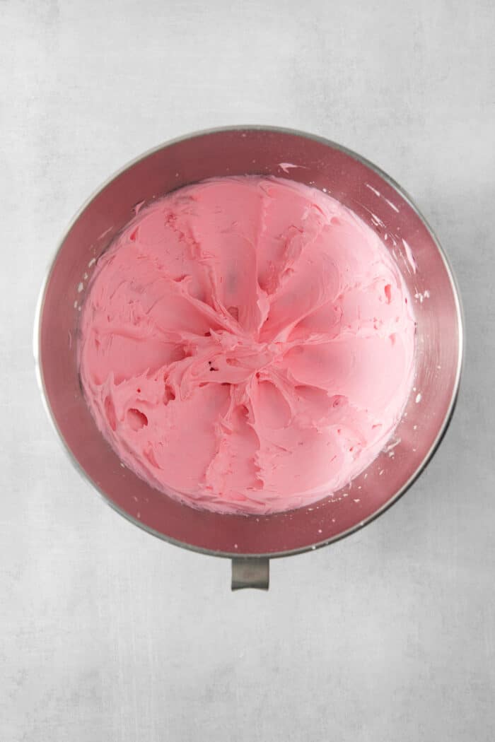 Strawberry Cream Wafer Cookies feature delicate cream and butter cookies that sandwich a pink filling that's fragrant with strawberry extract. A metal bowl full of pink strawberry buttercream.