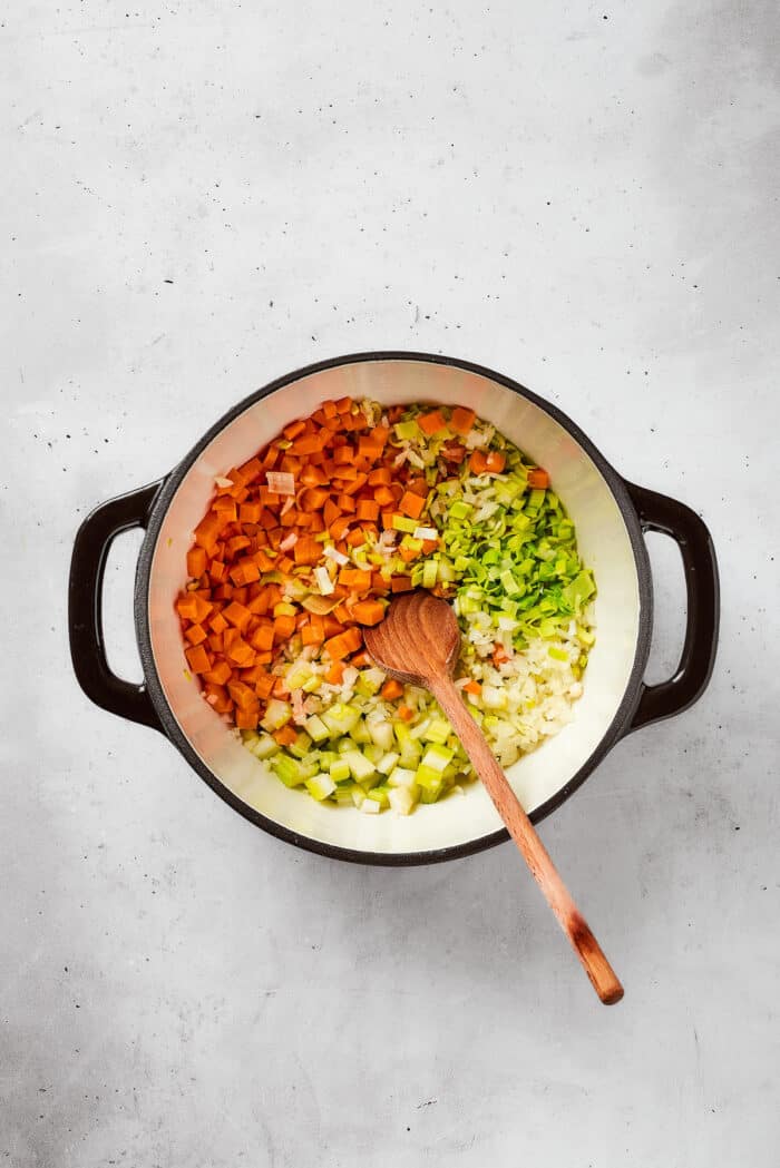 Greek-inspired Lemon Chicken Orzo Soup is fragrant with garlic and packed with tender chicken, vegetables, and delicate orzo pasta. Vegetables including carrots and celery are added to a soup pot.