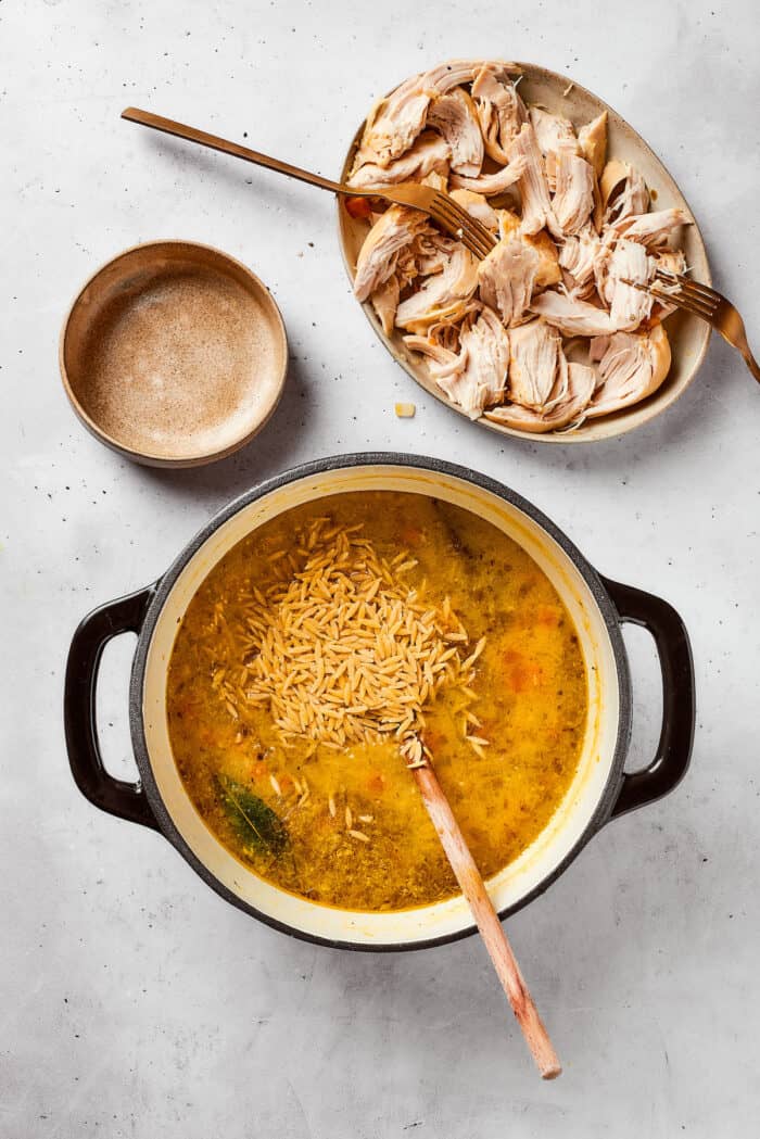 Greek-inspired Lemon Chicken Orzo Soup is fragrant with garlic and packed with tender chicken, vegetables, and delicate orzo pasta. Dried orzo is added to a pot of lemon chicken orzo soup.