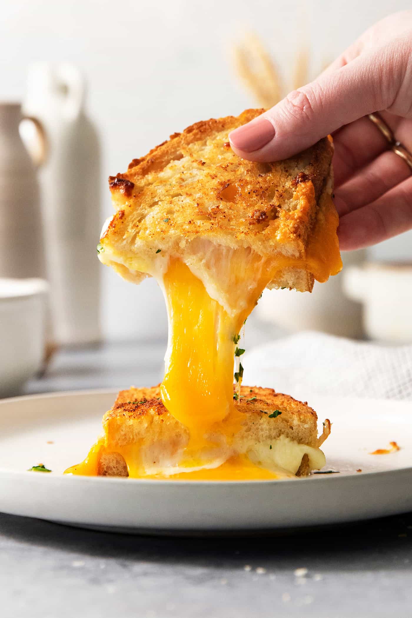 Air Fryer Grilled Cheese | Easy Cheesy Grilled Cheese Recipe! A hand pulls apart a piece of air fryer grilled cheese to show the melted cheese inside.