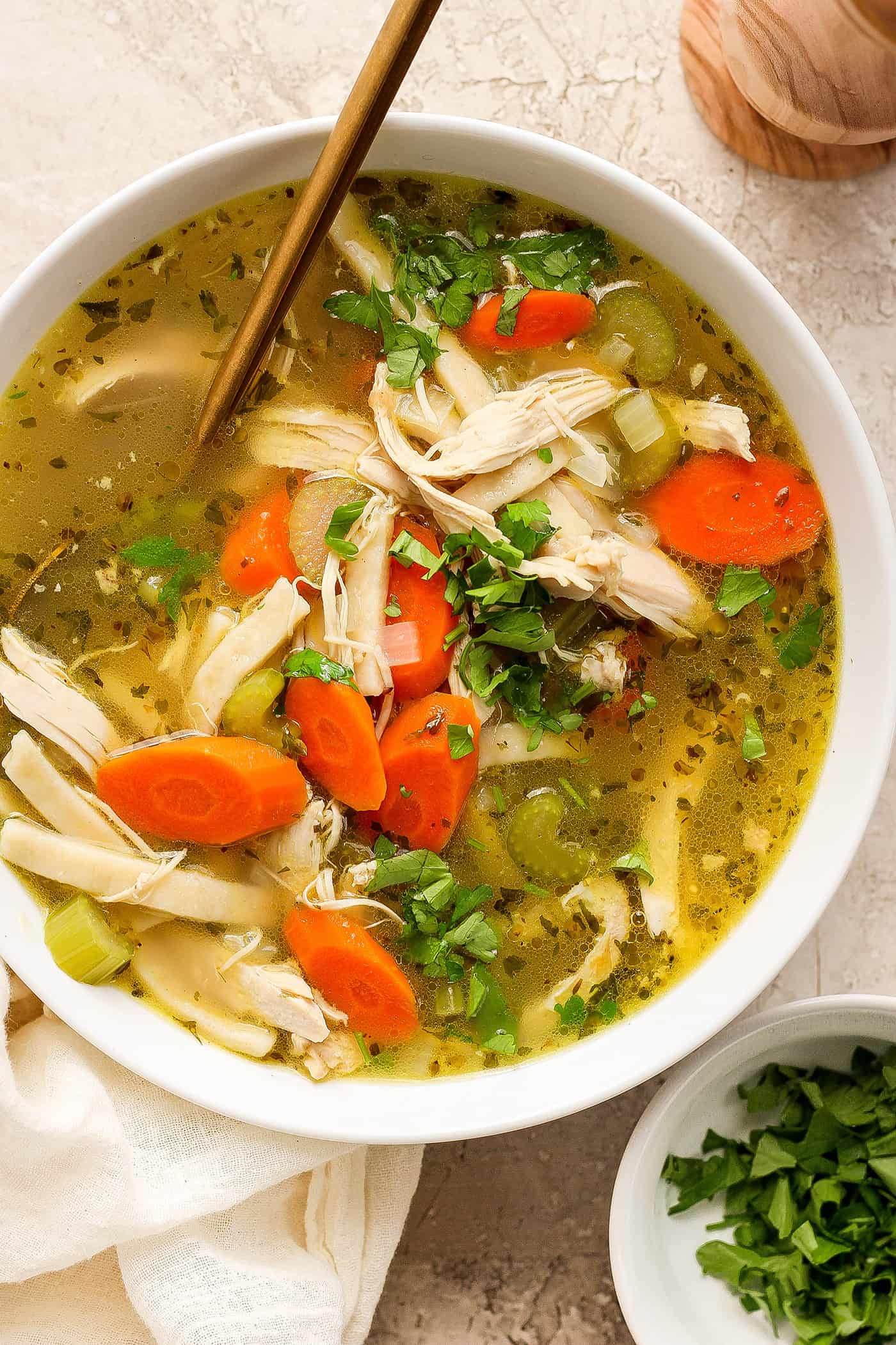 This homemade Chicken Noodle Soup is an easy classic with from-scratch chicken broth loaded with tender chicken, vegetables, and egg noodles. Chunks of chicken and vegetables are seen in a bowl of chicken noodle soup.