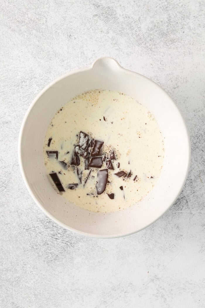 This easy Chocolate Ganache recipe is a versatile staple, perfect for so many things – from cakes to tart fillings to drizzling over coffee! Chopped chocolate is added to a bowl of hot cream for chocolate ganache.
