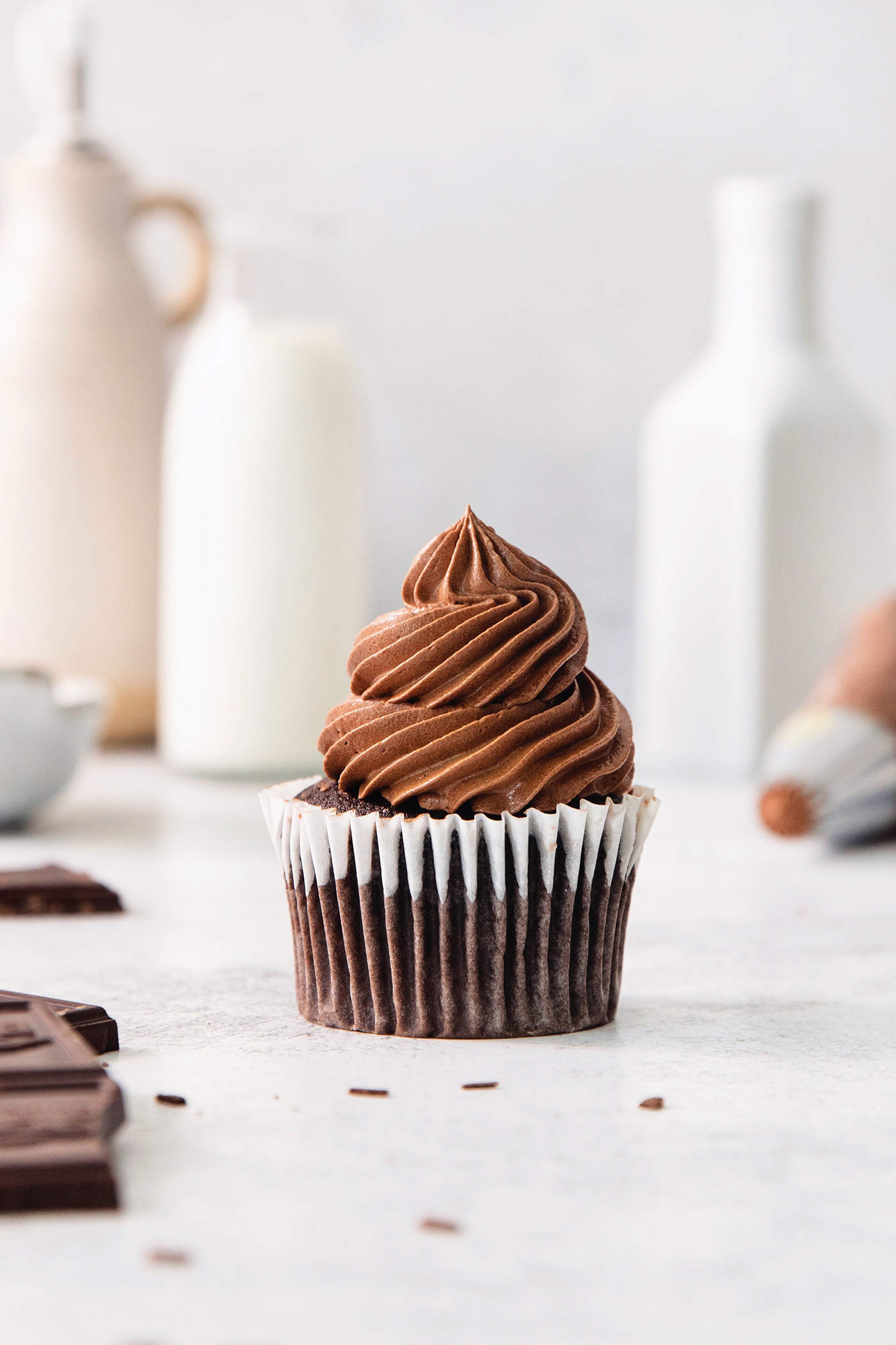 This easy Chocolate Ganache recipe is a versatile staple, perfect for so many things – from cakes to tart fillings to drizzling over coffee! A chocolate cupcakes topped with chocolate ganache frosting.
