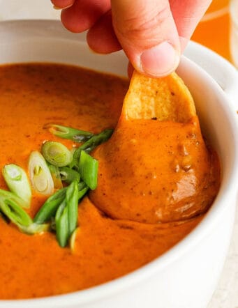dipping a chip into a bowl of chili cheese dip