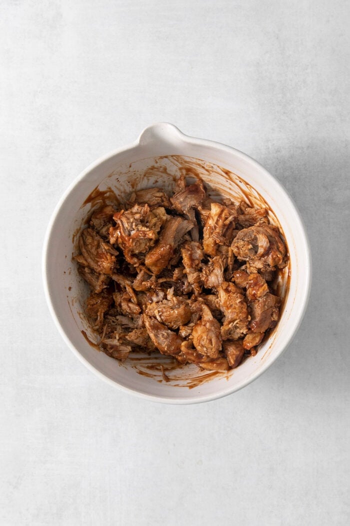 This easy Pulled Pork Mac and Cheese is super decadent with rich and creamy 3-cheese macaroni and cheese plus tender shredded pork. A white bowl full of pulled pork.