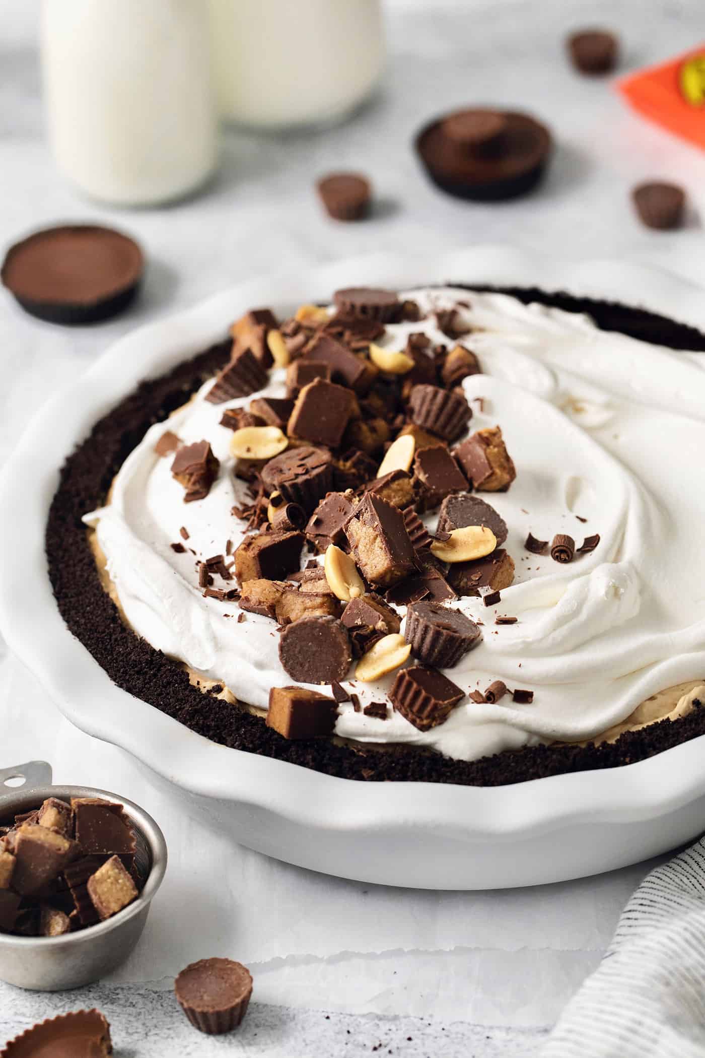 This no-bake Reese’s Pie features a crisp Oreo crust and a creamy peanut butter filling finished with whipped topping and Reese’s cups. A Reeses pie topped with whipped topping and chopped peanut butter cups.