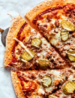 Half of a sliced cheeseburger pizza on a white background.