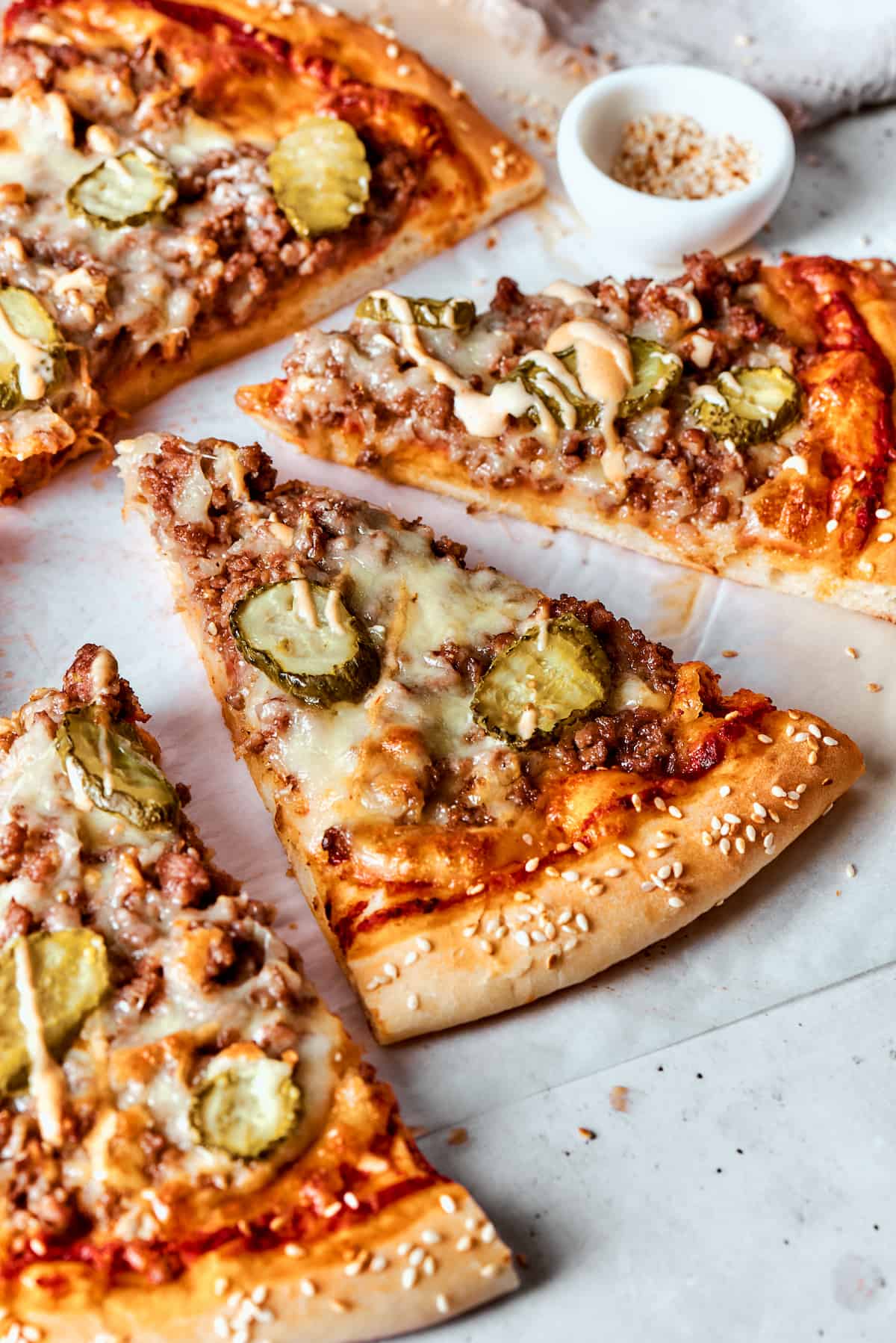 This Cheeseburger Pizza recipe turns your favorite burger into pizza! Top homemade dough with pizza sauce, ground beef, cheese, and pickles. Cut slices of cheeseburger pizza topped with pickles.