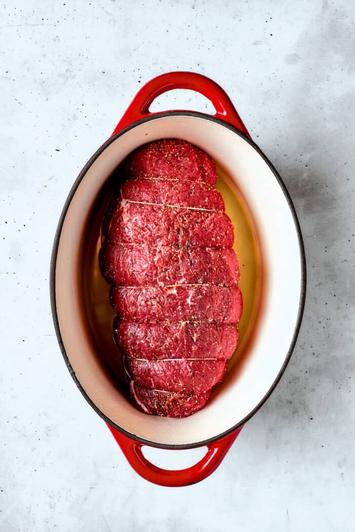 This ultra-juicy Sirloin Tip Roast recipe makes perfectly tender meat every time with plenty of garlic and fresh herbs for added flavor. The uncooked roast is added to the pot.