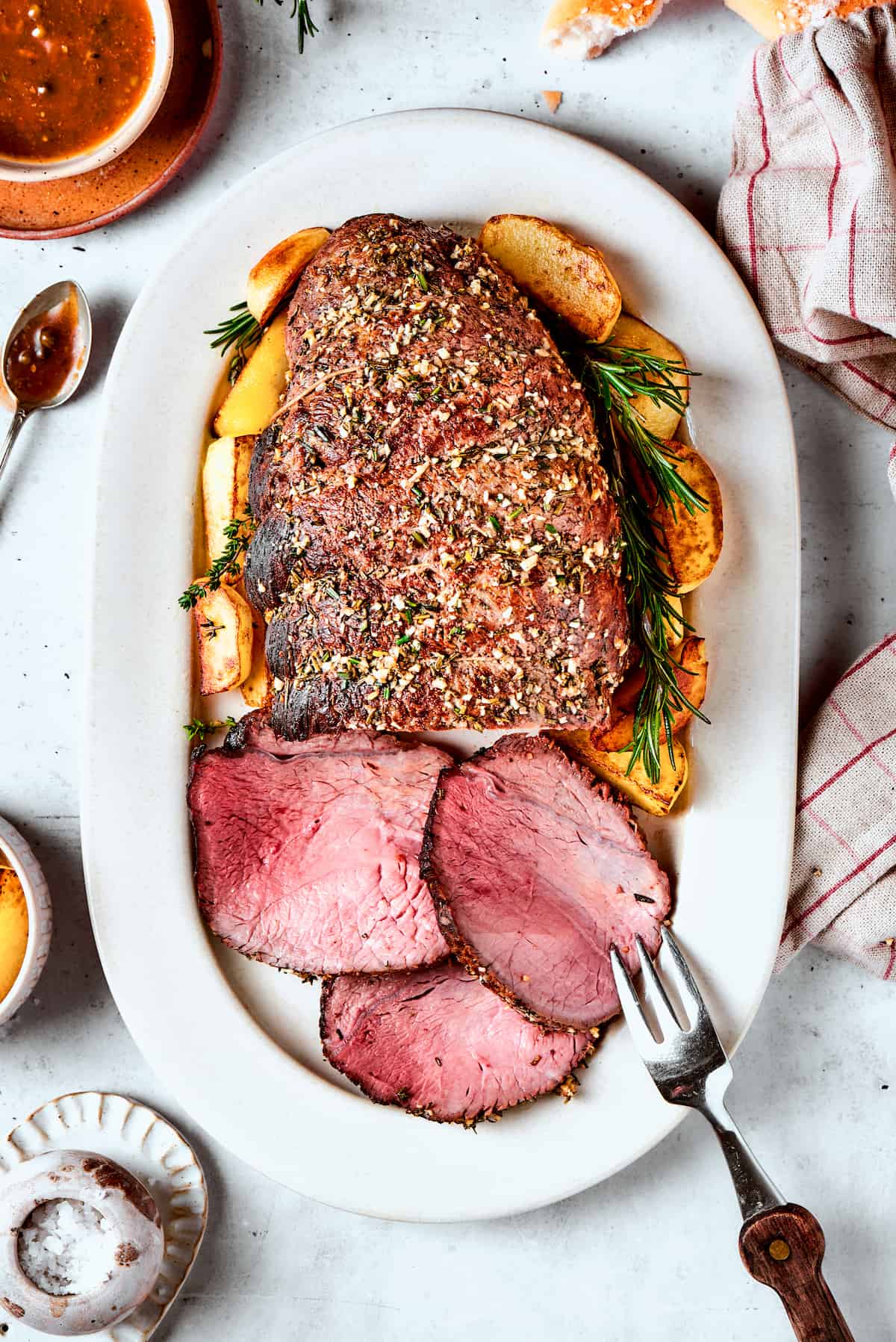 This ultra-juicy Sirloin Tip Roast recipe makes perfectly tender meat every time with plenty of garlic and fresh herbs for added flavor. A white platter holds a sirloin tip roast with three slices cut from it.