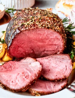 A sirloin tip roast on a platter with slices of roast.