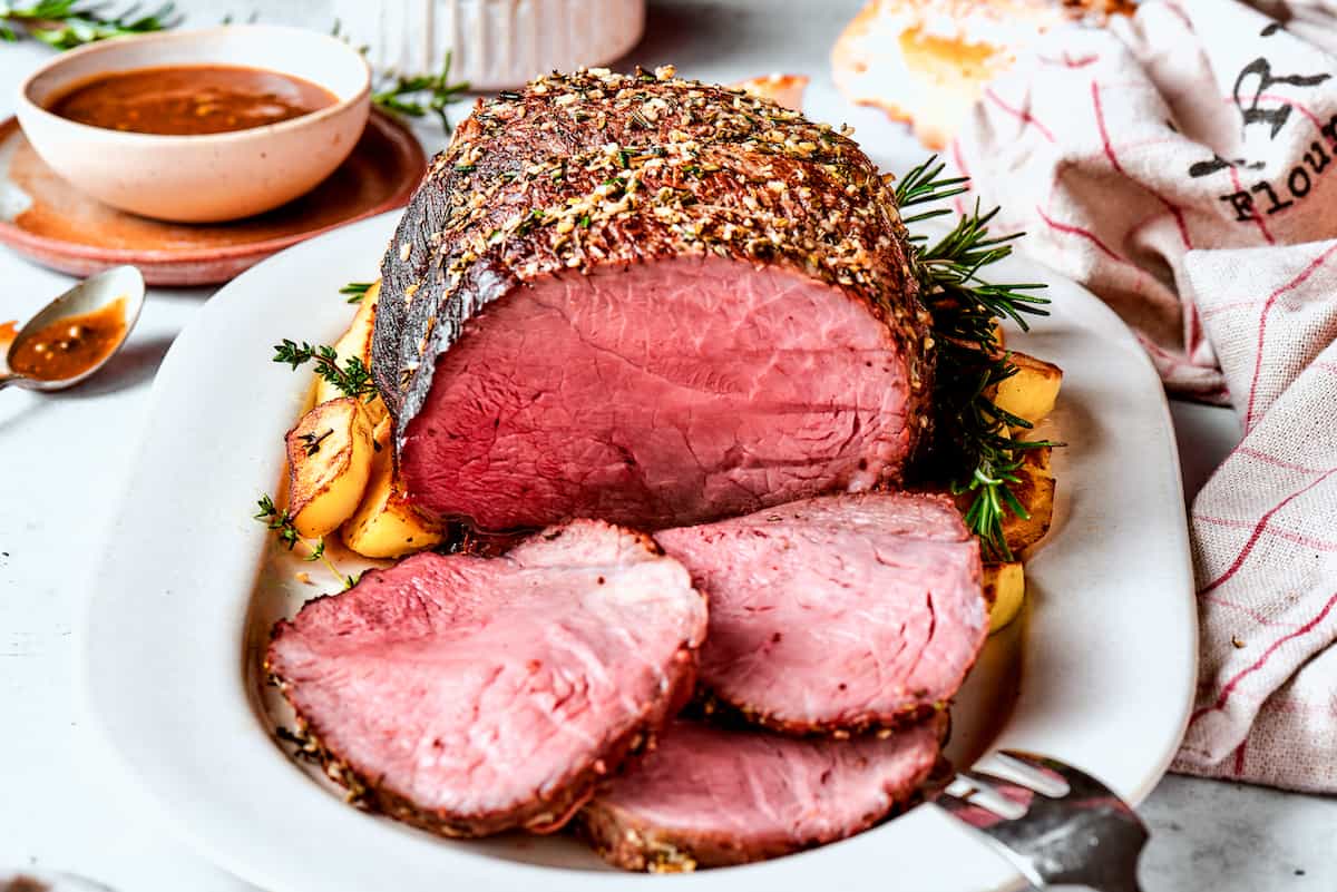 A sirloin tip roast on a platter with slices of roast.