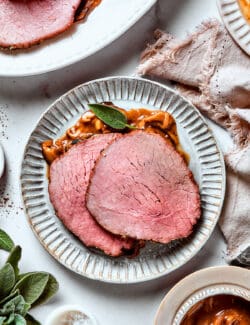Two slices of top round roast with gravy are served on a plate.