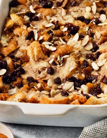 A baking dish full of capirotada topped with raisins and almonds.