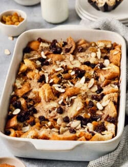 A baking dish full of capirotada topped with raisins and almonds.