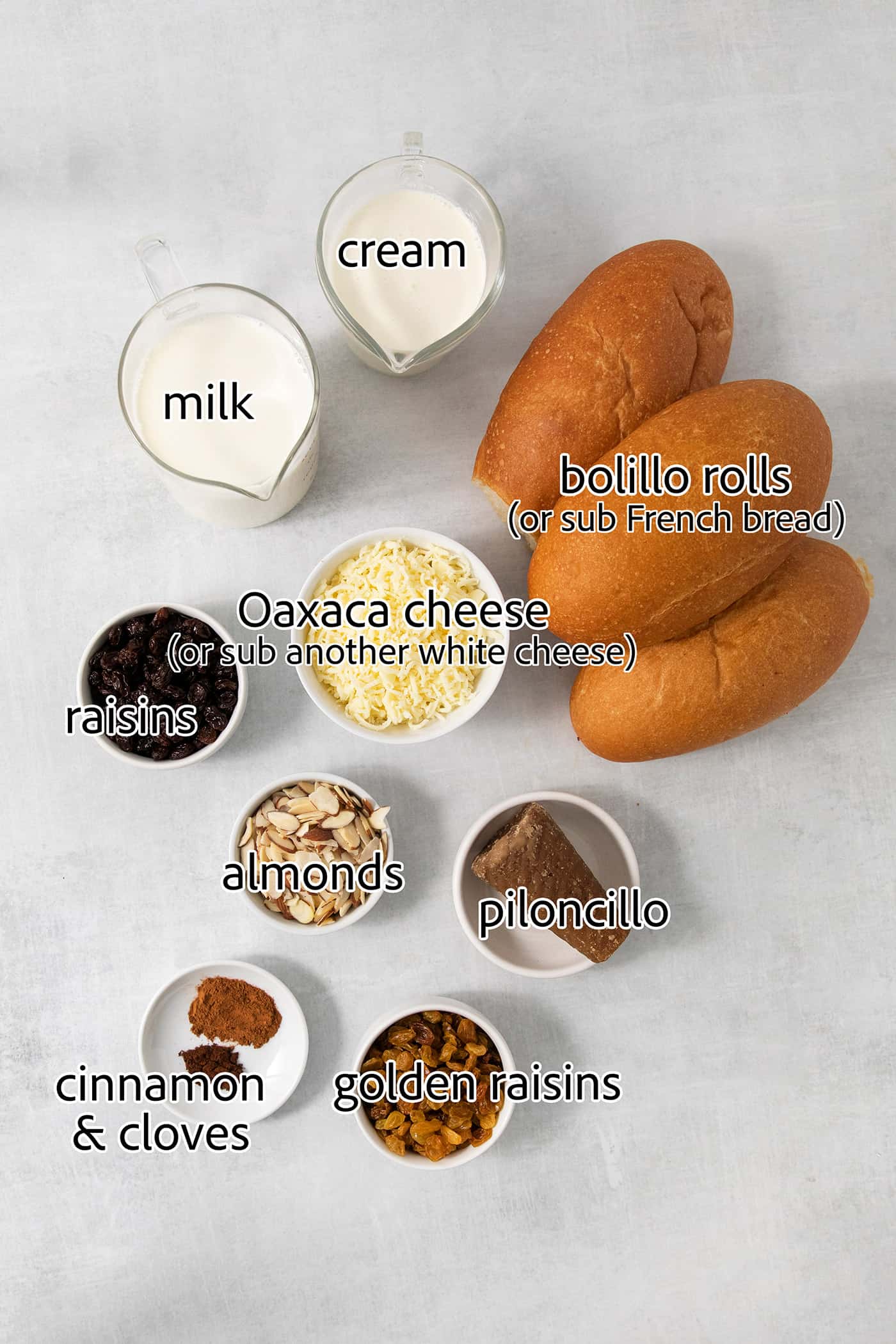 Capirotada, or Mexican Bread Pudding, features layers of crusty bread, raisins, sliced almonds, and cheese soaked in spiced sweet cream. The ingredients for capirotada are shown: rolls, milk, cream, cheese, raisins, golden raisins, sliced almonds, spices.
