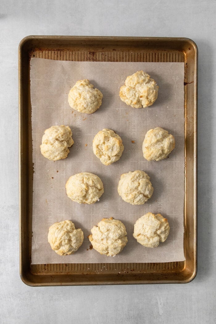 This homemade Chicken Pot Pie Soup recipe features a creamy broth that’s loaded with chicken and vegetables and topped with biscuits. The biscuits are shown on the baking sheet after being baked.