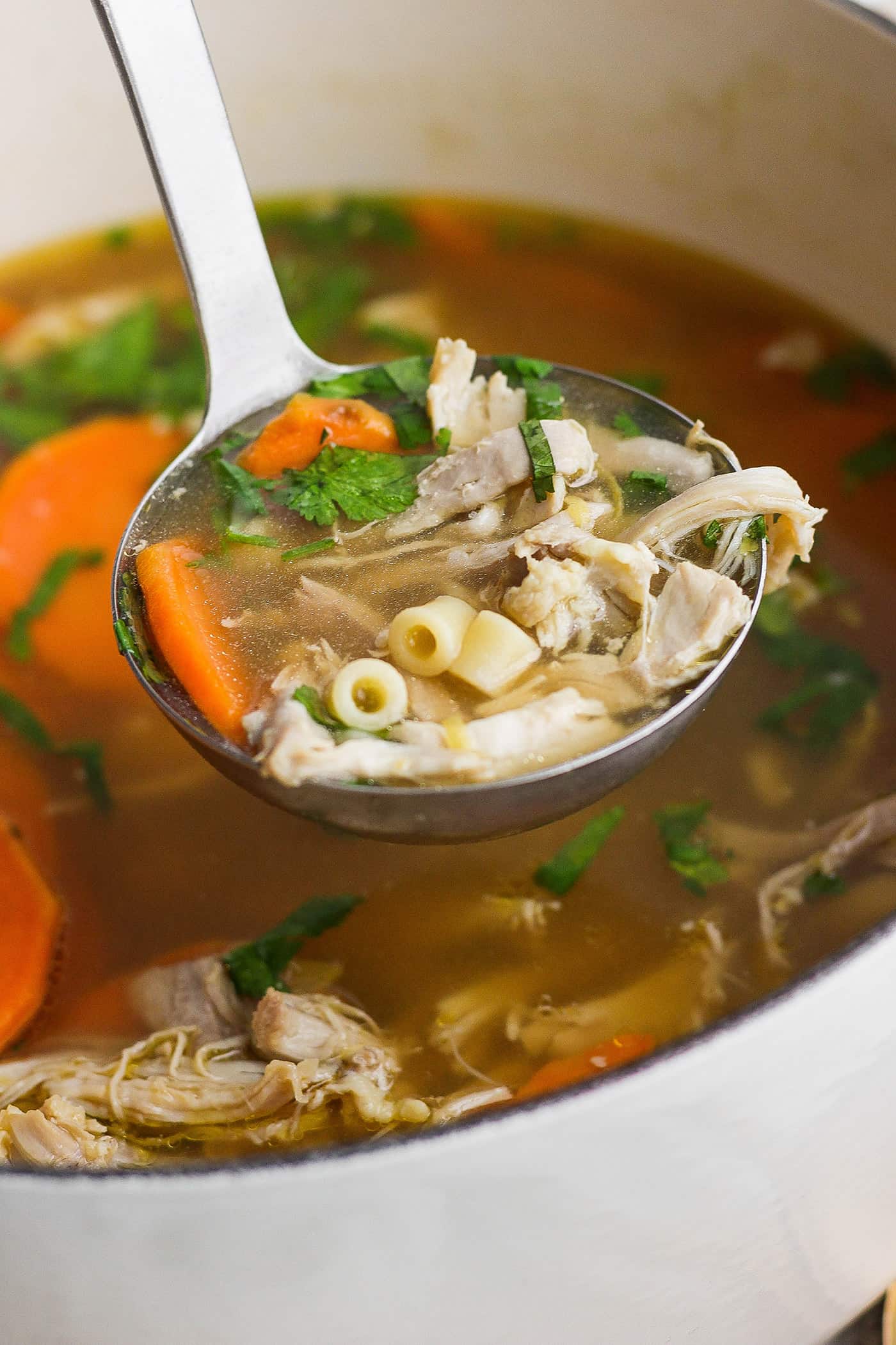 This zesty Chicken Ginger Soup recipe is brimming with fresh ginger, garlic, and lemon plus sweet potatoes, shredded chicken, and pasta. A ladleful of ginger chicken soup showing shredded chicken, pasta, and sweet potatoes.