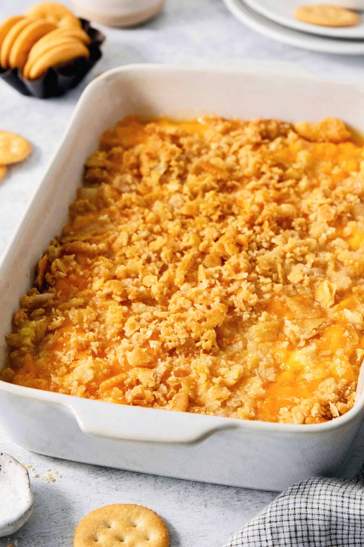 This easy Pineapple Casserole is a sweet and savory southern-inspired dish combining pineapple with cheese that pairs perfectly with BBQ. A white baking dish holds cracker-topped pineapple casserole.