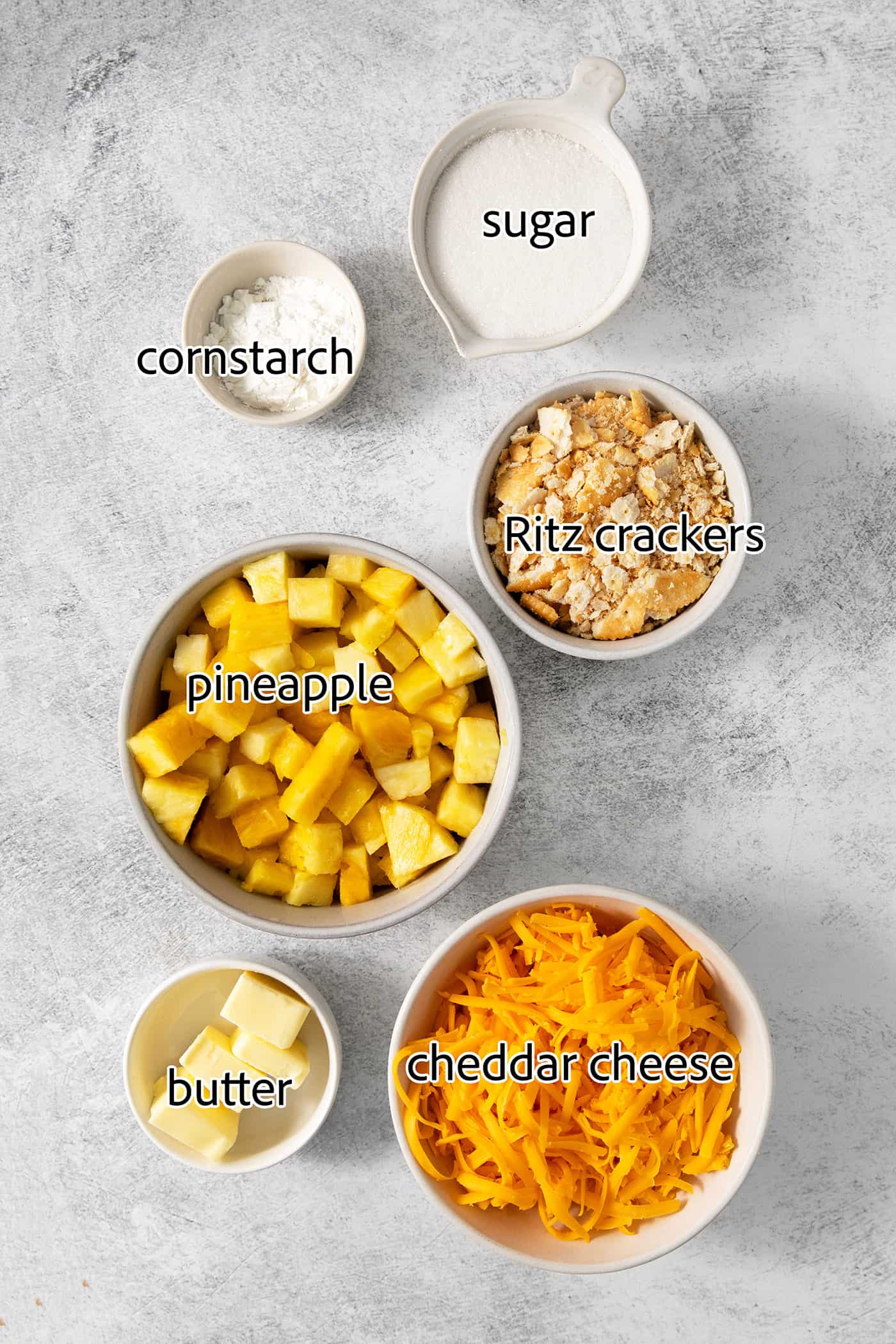 This easy Pineapple Casserole is a sweet and savory southern-inspired dish combining pineapple with cheese that pairs perfectly with BBQ. Ingredients needed to make pineapple casserole are shown: pineapple, cornstarch, butter, ritz crackers, cheddar cheese, sugar.
