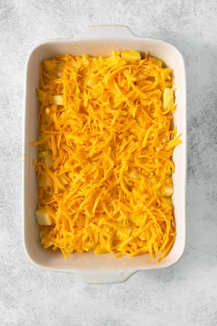 This easy Pineapple Casserole is a sweet and savory southern-inspired dish combining pineapple with cheese that pairs perfectly with BBQ. Shredded cheddar cheese tops the pineapple mixture in a white baking dish.