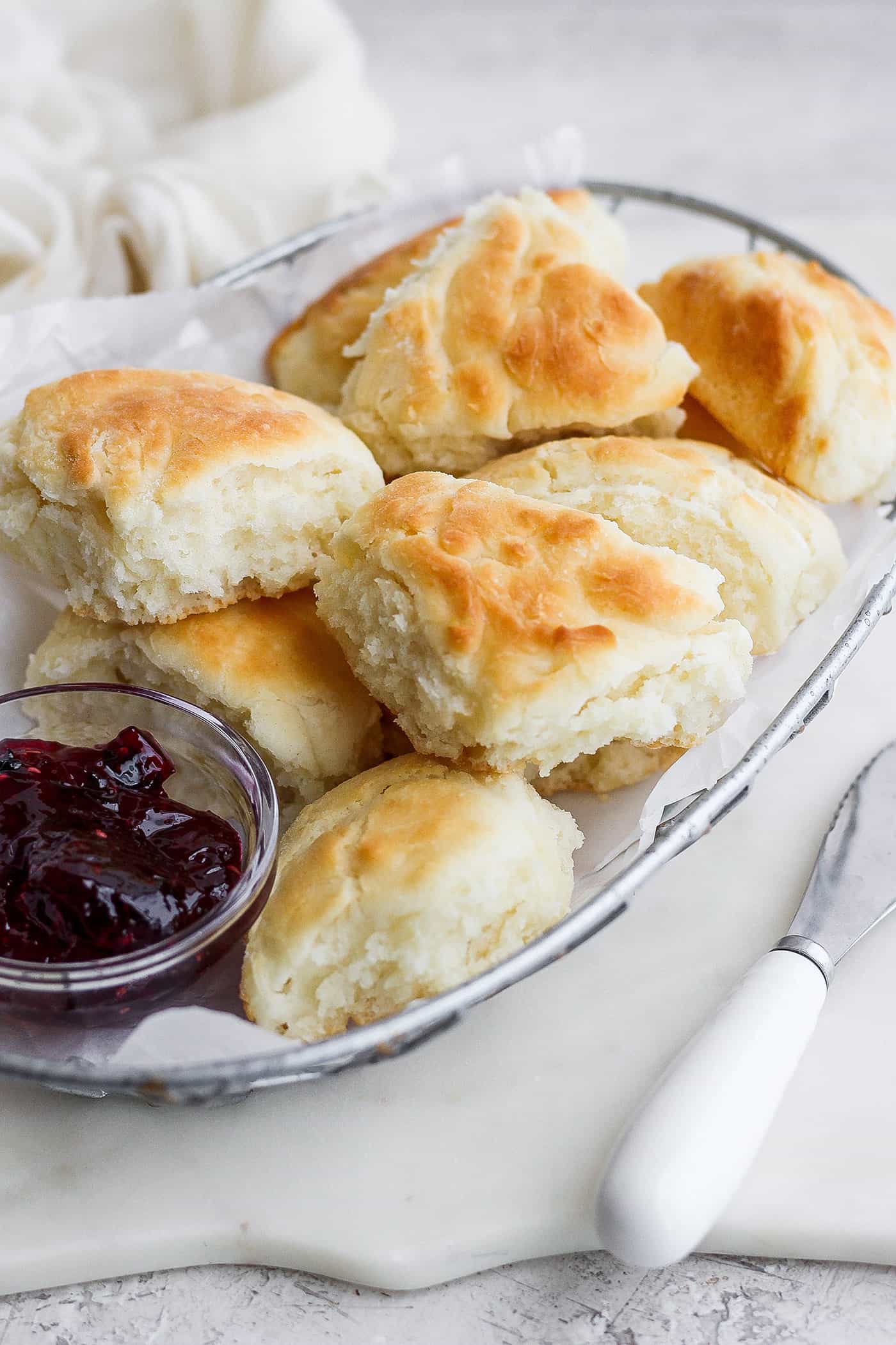 Flaky and light Touch of Grace Biscuits are made with White Lily flour to make unbelievably tender pull-apart biscuits. Touch of grace biscuits in a wire basket with a dish of jam.