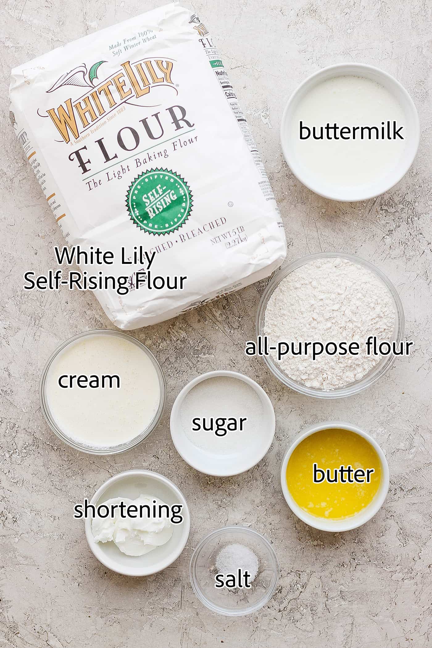 Flaky and light Touch of Grace Biscuits are made with White Lily flour to make unbelievably tender pull-apart biscuits. The ingredients needed to make touch of grace biscuits are shown: White Lily flour, butter, flour, sgar, cream, shortening, buttermilk, salt.