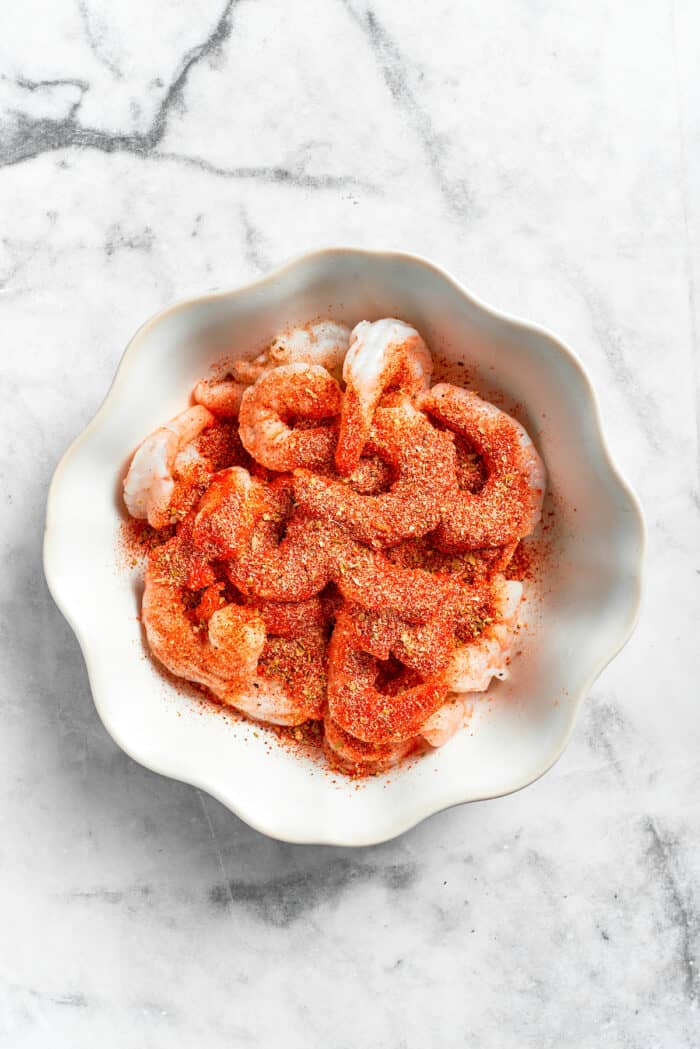 This beautiful, smoky-spicy Cajun Shrimp Pasta recipe folds juicy shrimp into a creamy, Louisiana-inspired sauce. Seasoning shrimp in a bowl for cajun shrimp pasta.