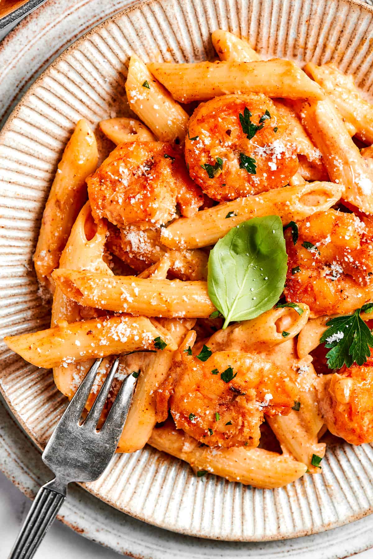 This beautiful, smoky-spicy Cajun Shrimp Pasta recipe folds juicy shrimp into a creamy, Louisiana-inspired sauce. A close up of red cajun shrimp pasta with a fork.