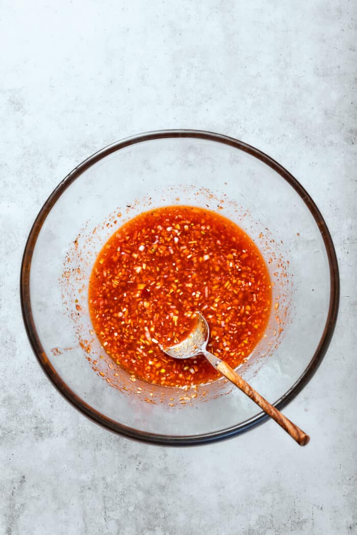 A spoon mixes together the marinade.