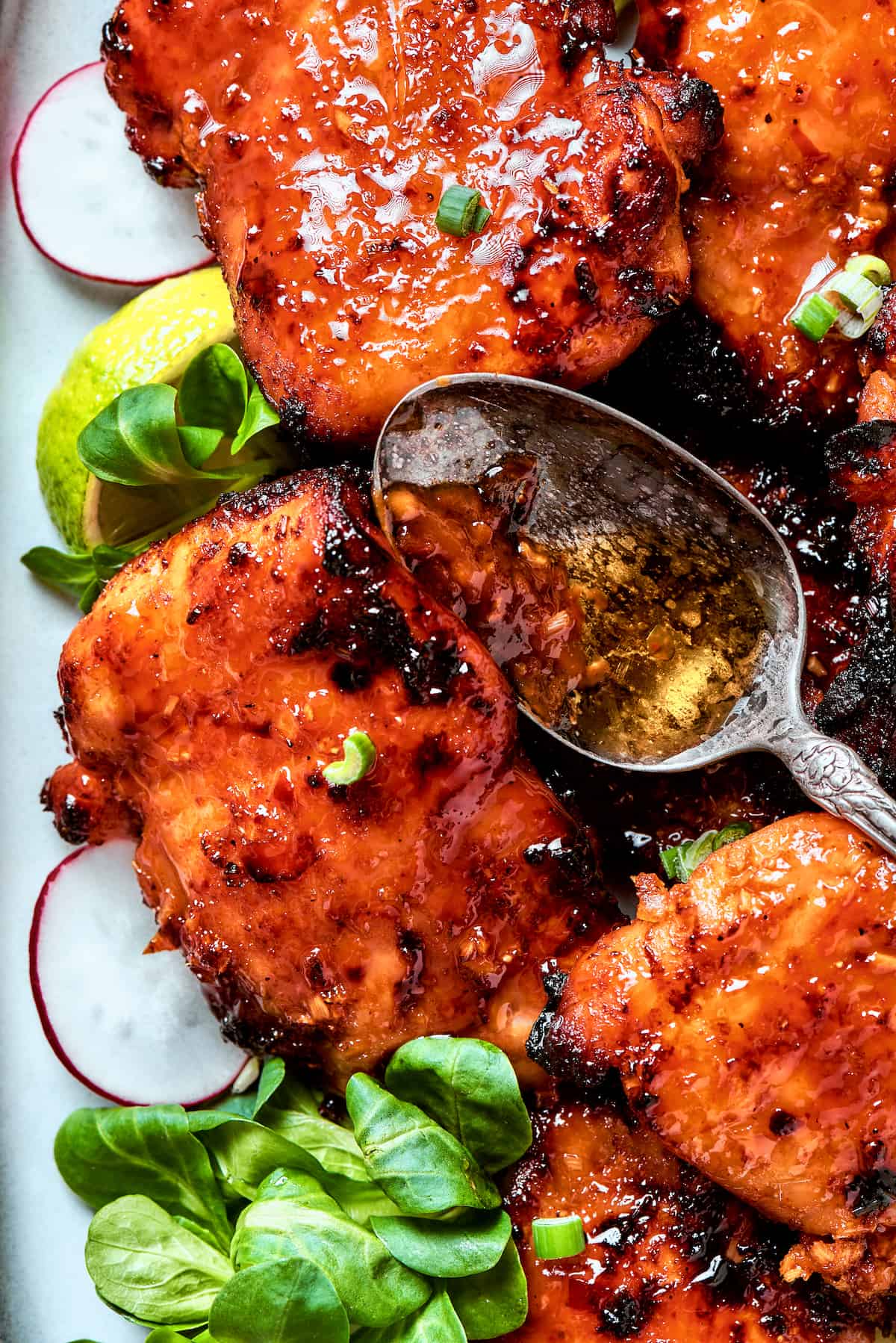 A spoon with sauce rests on top of lemongrass chicken.