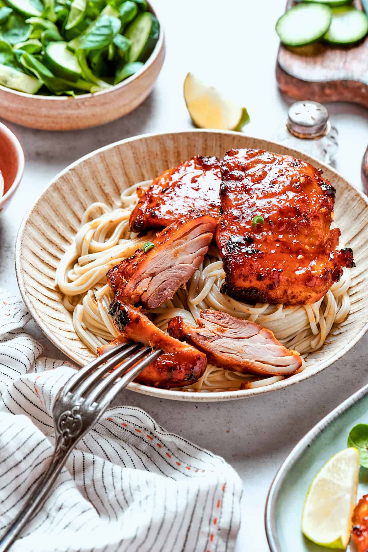 A bowl of lemongrass chicken over noodles with a fork.