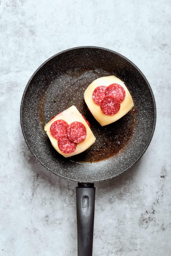 Pepperoni slices are added to the burgers.