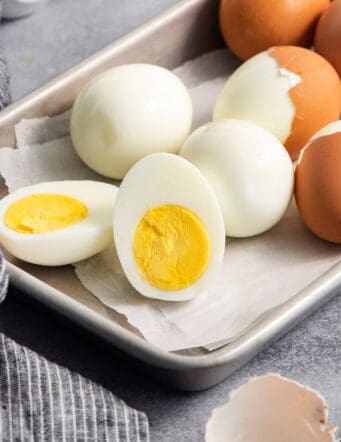hard boiled eggs on a rimmed pan, some are peeled and cut in half