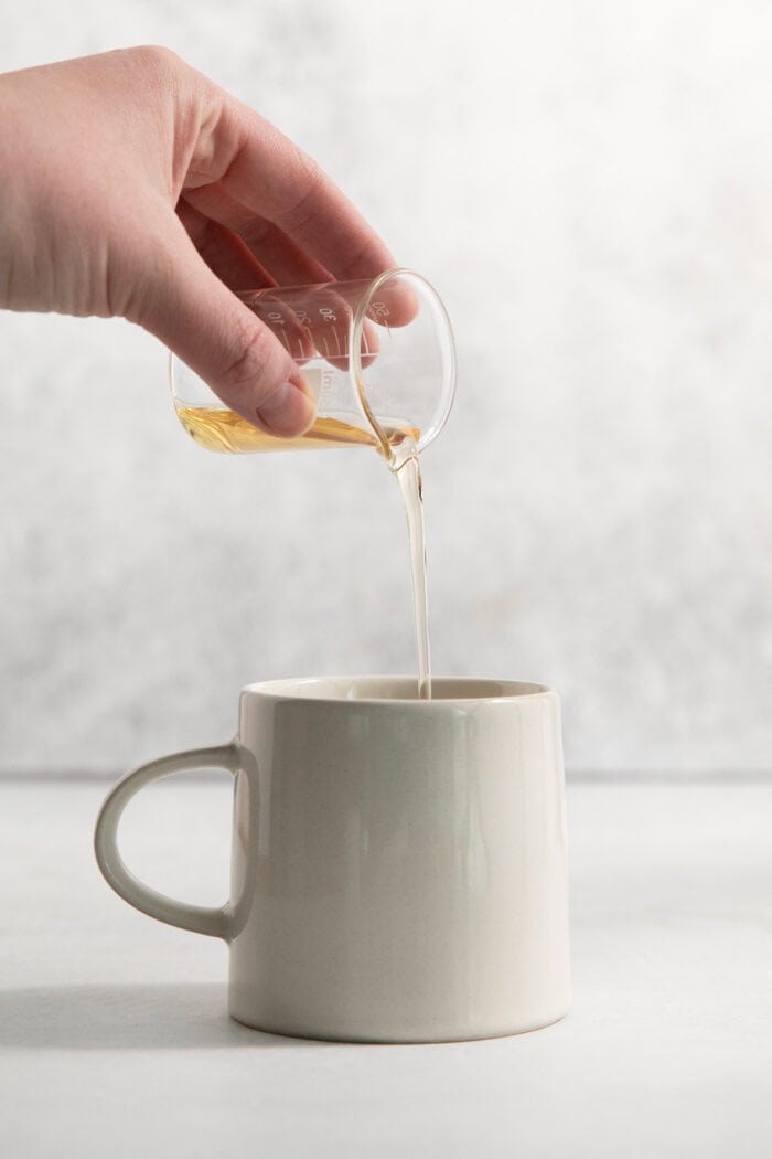This Lavender Latte mixes freshly brewed espresso, oat milk, and a sweet lavender simple syrup to create a copycat Starbucks lavender latte. Lavender simple syrup is poured into a mug.