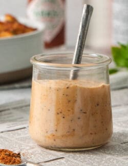 A glass jar holds shrimp dipping sauce with a spoon sticking out of it.