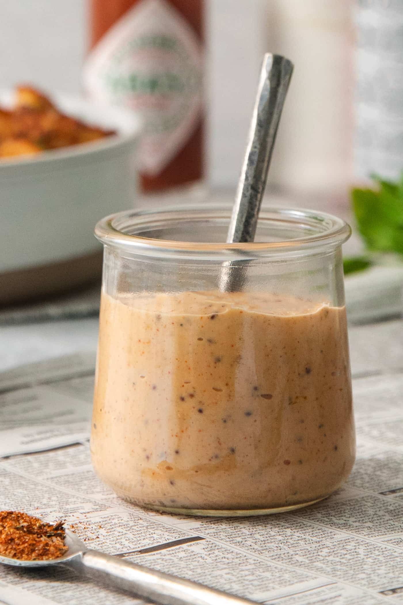A glass jar holds shrimp dipping sauce with a spoon sticking out of it.