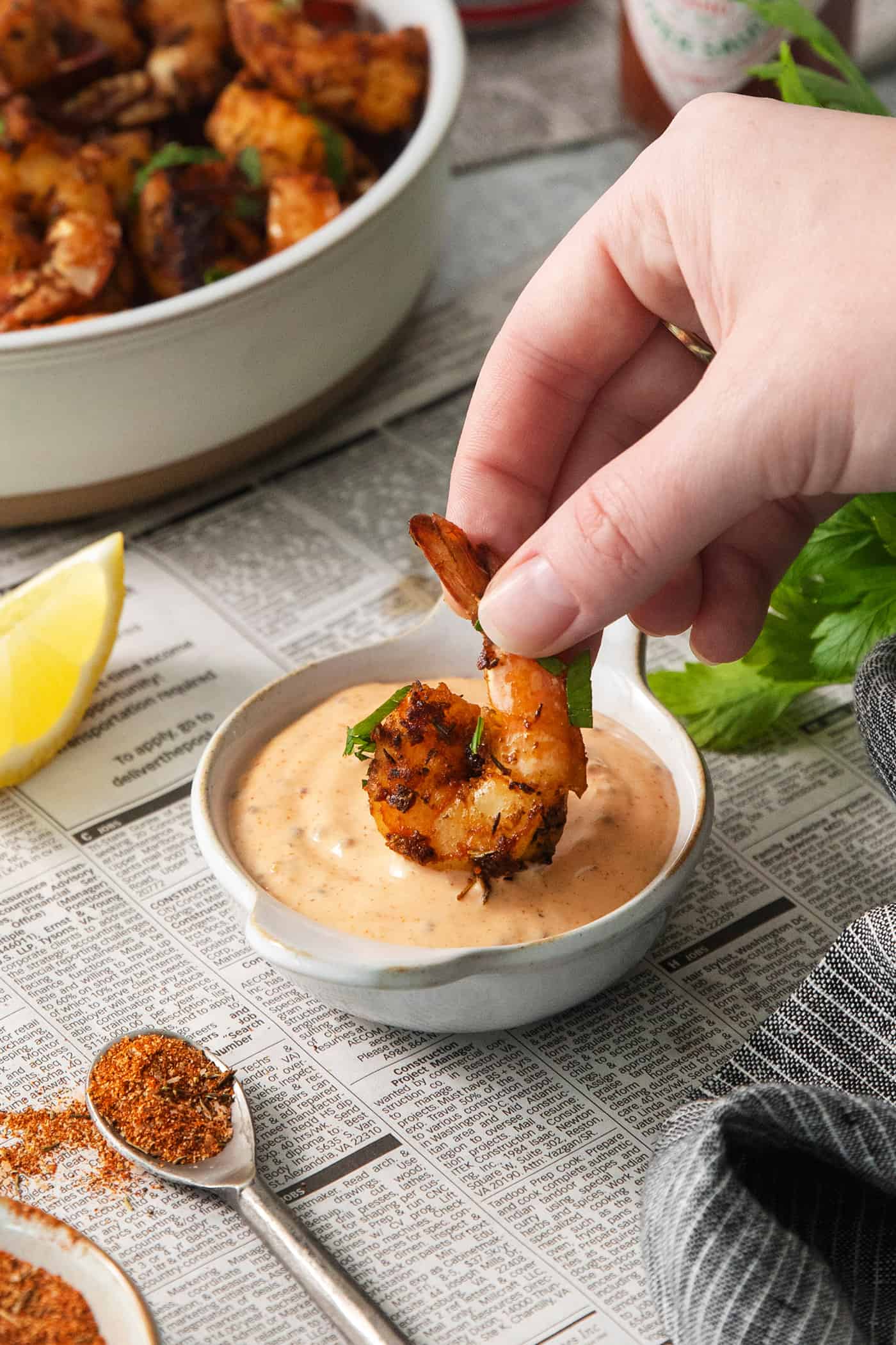 This easy and creamy Shrimp Dipping Sauce the perfect accompaniment for your favorite shrimp recipes, and feature lemon and a kick of heat. A hand dips a piece of blackened shrimp into a bowl of shrimp dipping sauce.