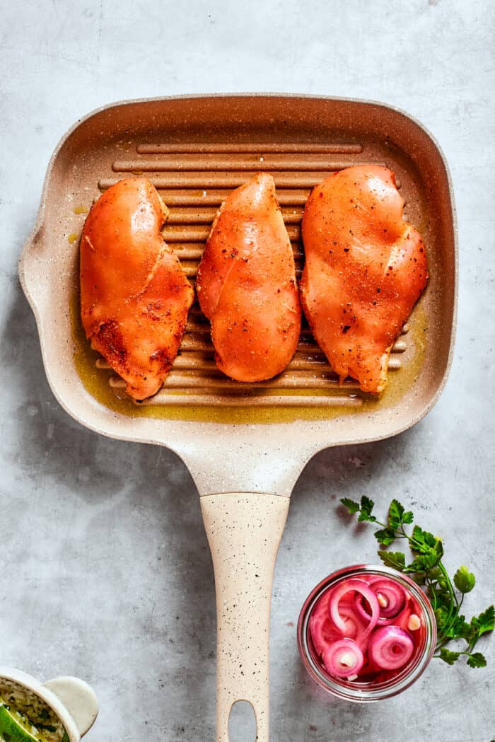Juicy Honey Mustard Chicken Kabobs are slicked in a smoky honey mustard sauce and cooked to perfection on the grill. Three chicken breasts cook on a grill pan.