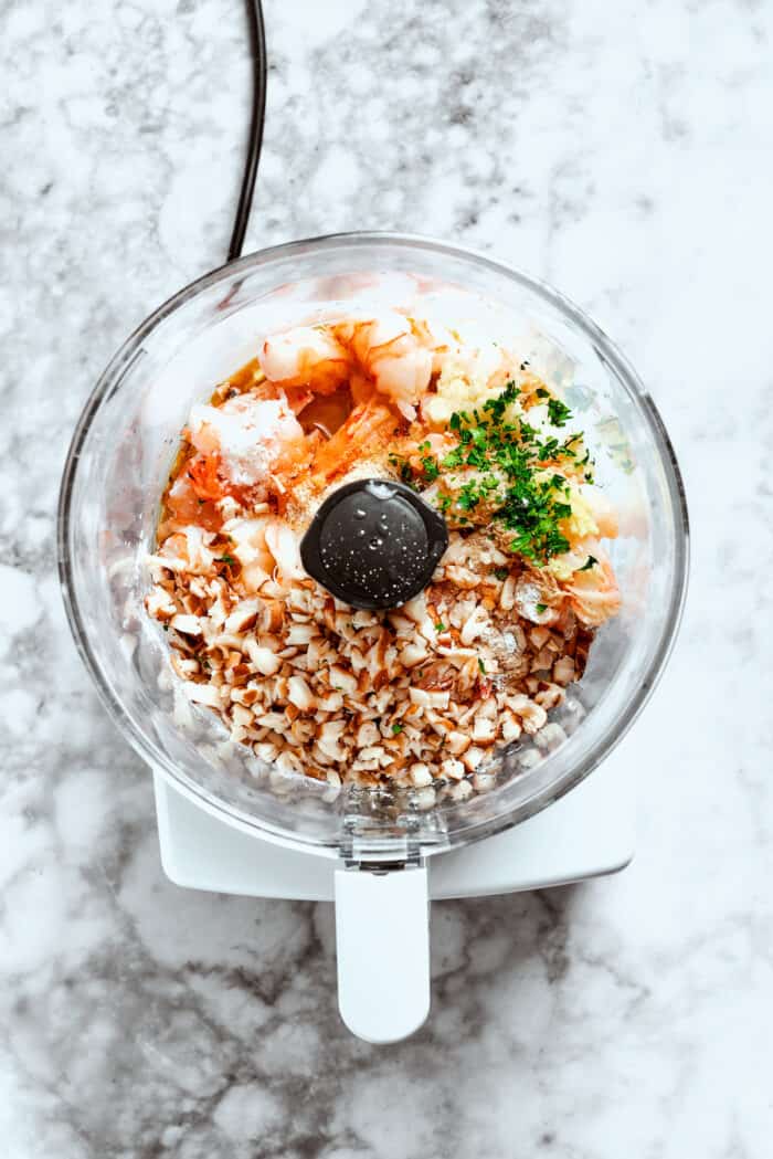The filling ingredients for shrimp shumai are added to a food processor and pulsed.
