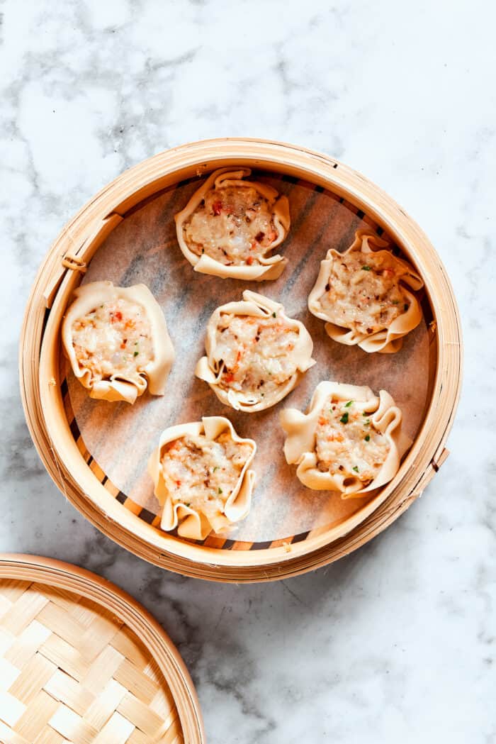 A bamboo steamer with 5 pieces of shrimp shumai.