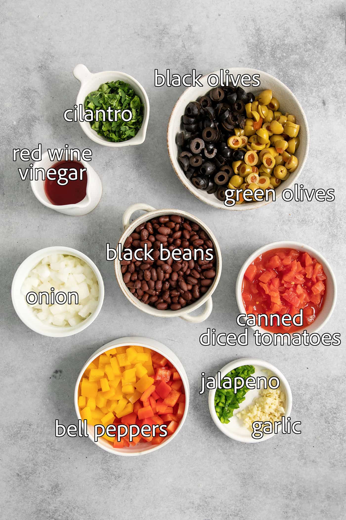Scoop up this easy, versatile Black Bean Salsa with tortilla chips, dollop a spoonful on top of nachos, or use it as a taco filling! Ingredients for black bean salsa are portioned out and labeled: black beans, olives, onion, vinegar, cilantro, canned tomatoes, garlic, cilantro.