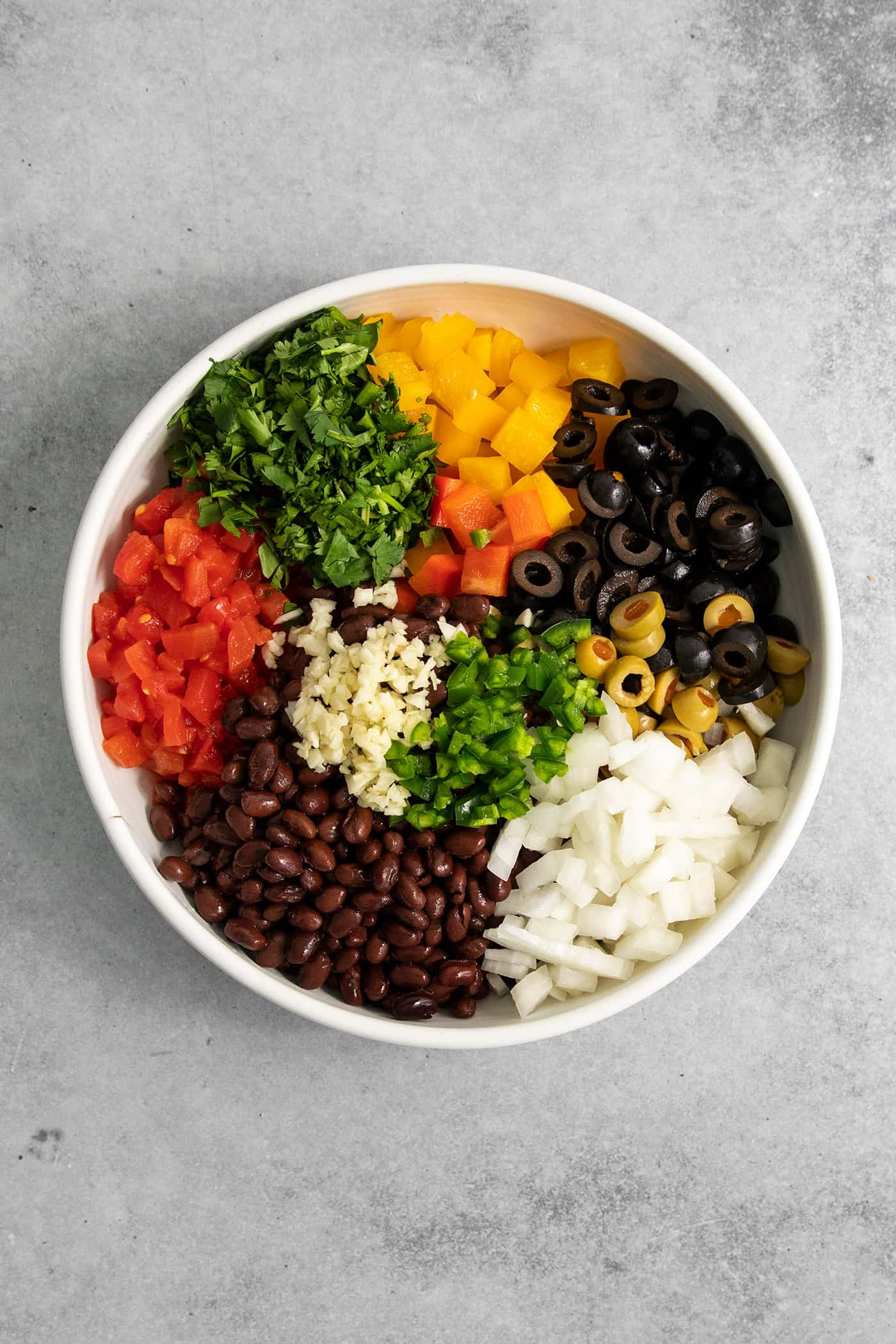 Scoop up this easy, versatile Black Bean Salsa with tortilla chips, dollop a spoonful on top of nachos, or use it as a taco filling! Black bean salsa components are added to a bowl to be mixed together.