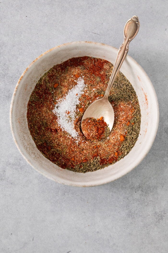 This homemade Blackened Seasoning recipe is rich, earthy, and slightly smoky with the perfect amount of heat! dried spices and herbs in a bowl, with a spoon