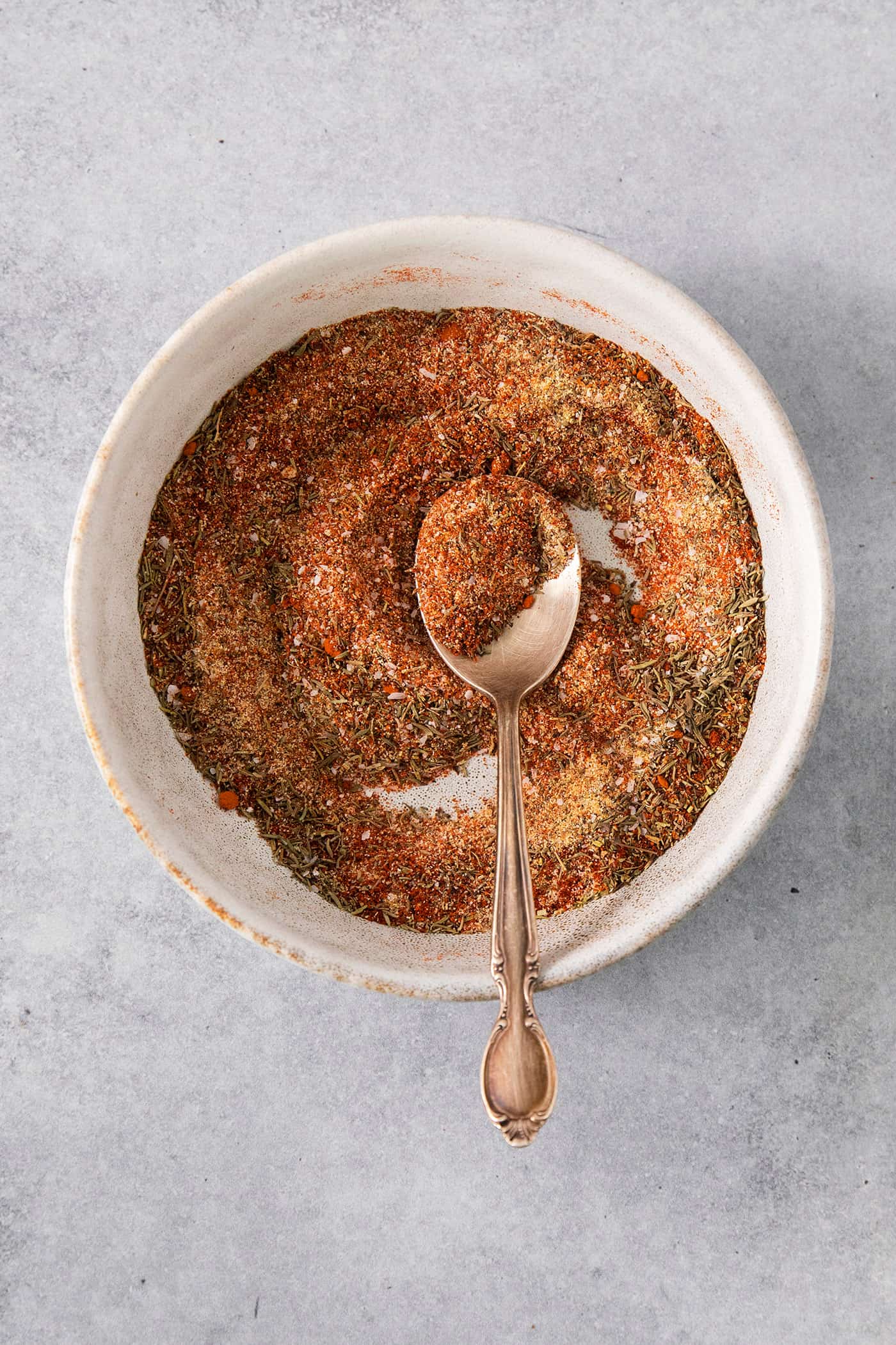 This homemade Blackened Seasoning recipe is rich, earthy, and slightly smoky with the perfect amount of heat! dried spices and herbs in a bowl, with a spoon